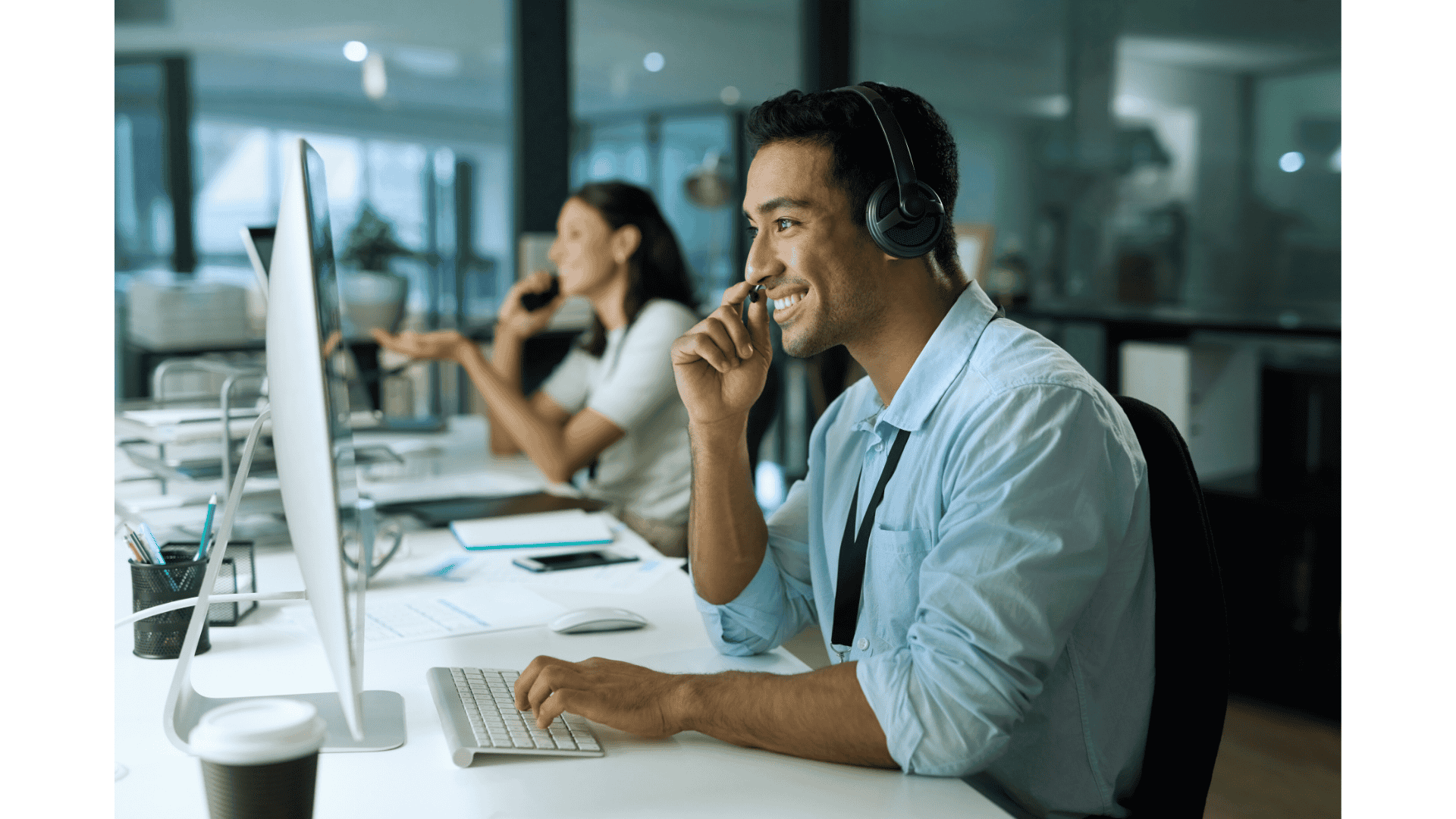 Junger Mitarbeiter vom Kundenservice am Arbeitsplatz während mit einem Kunden telefoniert. Diese Bild illustriert die im Artikel beschriebene Situation, in der Kunden währen des Telefongesprächs einer Aufzeichnung unterliegen und unter welchen Bedingungen des Datenschutzes und der DSGVO dies zulässig ist.